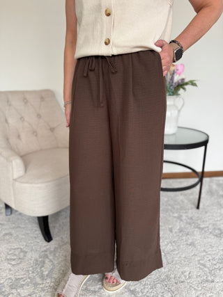 Lady standing wearing a chocolate brown drawstring pant.