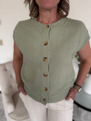 Woman wearing button up cap sleeve sweater in olive.