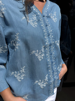 Woman is wearing a chambray embroidered top.