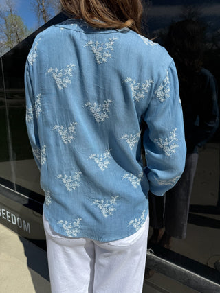Woman is wearing a chambray embroidered top.