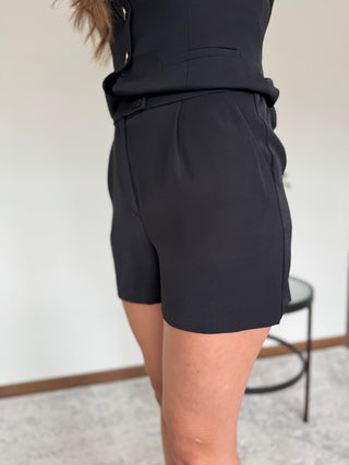 Person wearing black shorts with a neutral background
