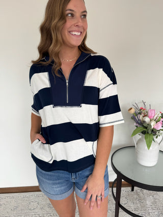 Woman wearing a navy and white striped shirt with denim shorts indoors.