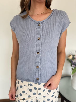 Woman standing in a mirror wearing a powder blue top and polka dot pants.