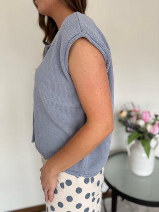 Woman standing in a mirror wearing a powder blue top and polka dot pants.