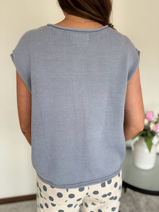 Woman standing in a mirror wearing a powder blue top and polka dot pants.