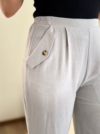 Lady wearing light blue linen pant with button front pocket.