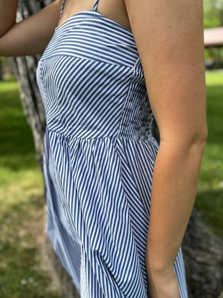Person wearing a blue and white striped dress in an outdoor setting