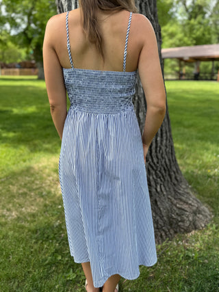 Woman wearing a blue and white striped dress standing in a park.