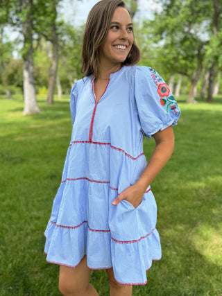Woman wearing a light blue dress with floral embroidery in a park