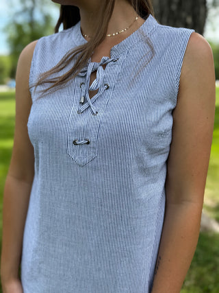 Person wearing a blue and white striped sleeveless top with a blurred green outdoor background
