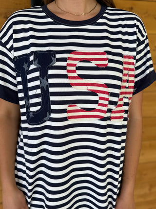 Person wearing a striped t-shirt with 'US' letters on a wooden floor background