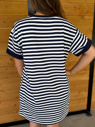 Person wearing a black and white striped dress against a wooden background