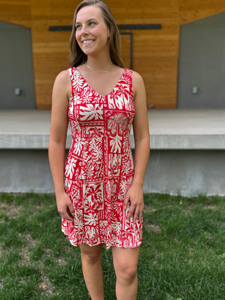 Woman wearing a red and white patterned dress standing outdoors.