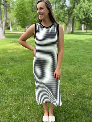 Woman wearing a black and white striped dress standing in a park.