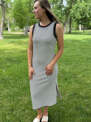 Woman wearing a black and white striped dress standing in a park.