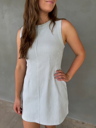 Woman wearing a white sleeveless dress against a gray background