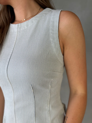 Close-up of a person wearing a sleeveless striped top against a neutral background