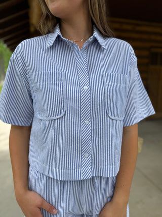 Person wearing a blue and white striped shirt and shorts set.