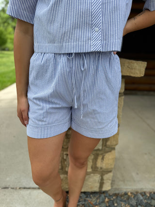 Person wearing a blue and white striped outfit with shorts, standing outdoors.