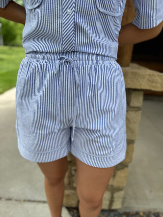 Person wearing a blue and white striped outfit with shorts outdoors.