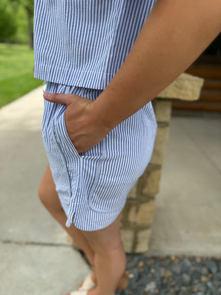 Person wearing blue and white striped shorts with a blurred background