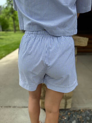 Person wearing a blue and white striped outfit with shorts and a shirt.