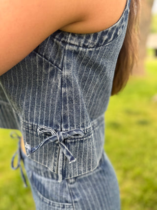 Close-up of a person wearing a blue denim dress with a blurred green background