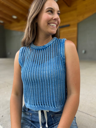Woman wearing a blue sleeveless knitted top outdoors