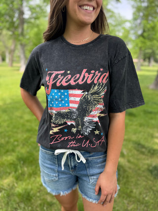 Person wearing a black t-shirt with an eagle and American flag design outdoors.