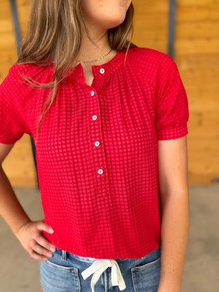 Person wearing a red checkered shirt with a blurred background