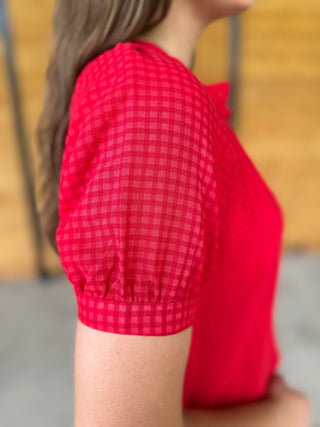 Red checkered blouse worn by a person with a blurred background