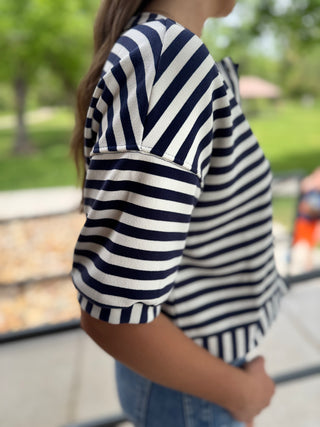 Person wearing a navy and white striped shirt with a blurred outdoor background