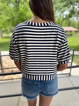 Person wearing a navy and white striped shirt with denim shorts in an outdoor setting