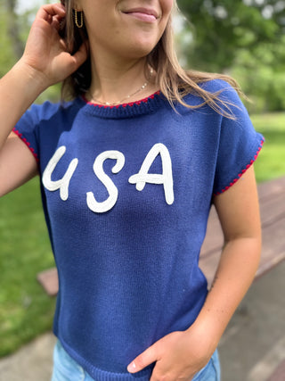Person wearing a blue sweater with 'USA' text outdoors