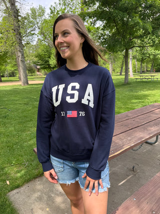 Woman wearing a navy blue 'USA' sweatshirt in a park setting