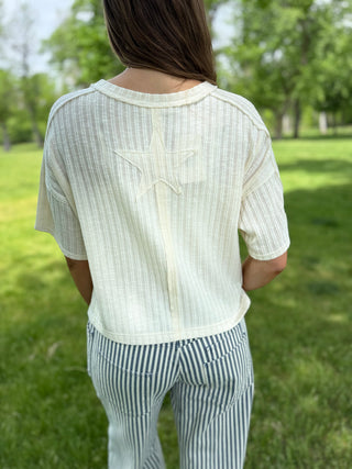 Person wearing a white blouse with a star design outdoors on a grassy area