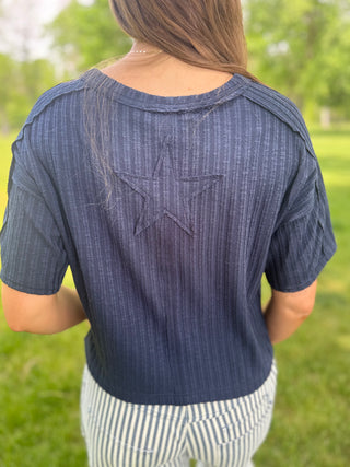 Person wearing a blue striped shirt with a star design outdoors