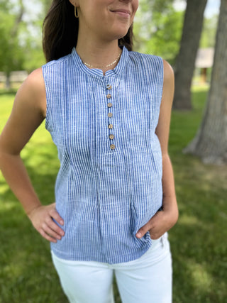 Woman wearing a blue striped sleeveless top in an outdoor setting