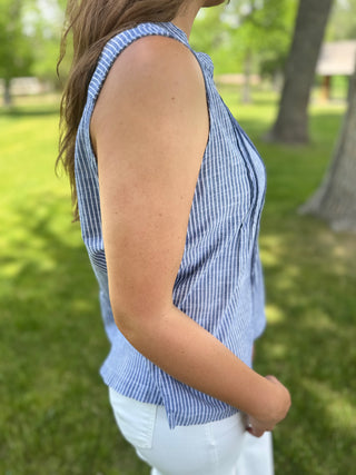 Person wearing a blue striped sleeveless top in a park setting
