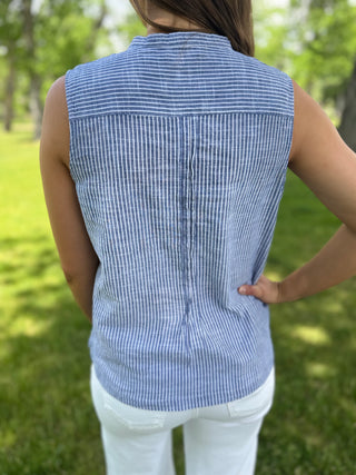 Person wearing a blue striped sleeveless shirt in a grassy outdoor setting