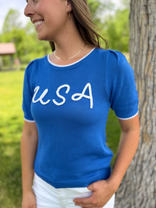 Woman wearing a blue sweater with 'USA' text outdoors