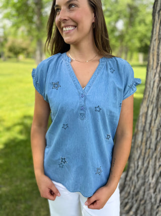 Woman wearing a blue denim top with star patterns in a park setting