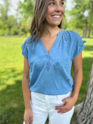 Woman wearing a blue top with star patterns in a park setting