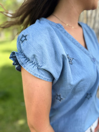 Person wearing a blue denim shirt with star patterns outdoors
