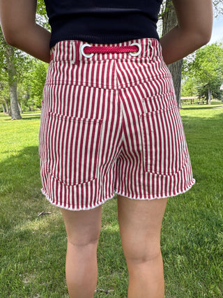 Red and white striped shorts worn by a person in a park setting