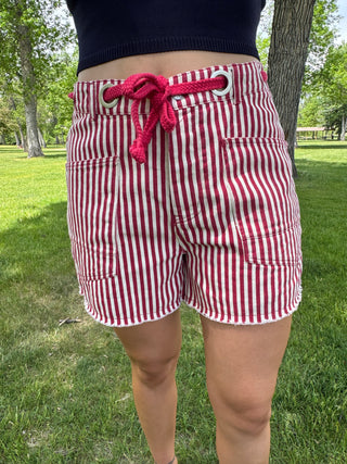 Red and white striped shorts with a pink drawstring worn by a person in a park.