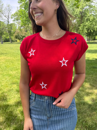 Person wearing a red t-shirt with star patterns outdoors