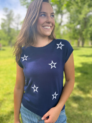 Woman wearing a navy blue t-shirt with white star patterns in an outdoor setting.