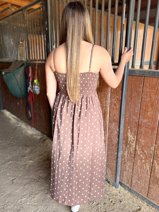 Woman in a polka dot dress standing next to a wooden stable door.