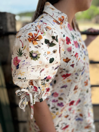 Person wearing a floral-patterned outfit with a blurred background